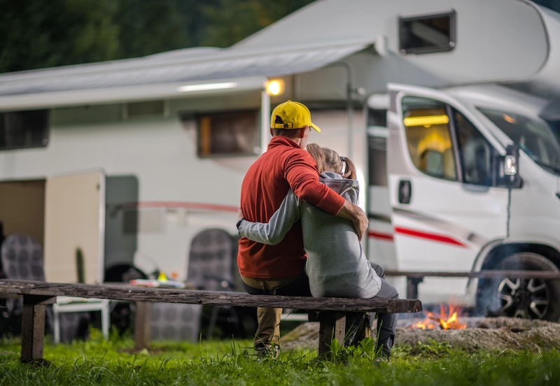 Family hugging around a fire next to an RV